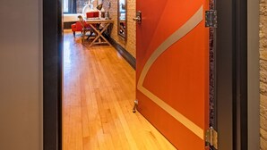 An interior hallway with a wooden floor, a red door labeled 'Two,' and a seating area with a table and chairs. - 124 Lofts #2 - Downtown Dundee - Walk to Dining (West Dundee)
