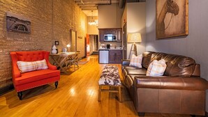 A cozy living room with a red armchair, a brown leather sofa, and a wooden bench. - 124 Lofts #2 - Downtown Dundee - Walk to Dining (West Dundee)