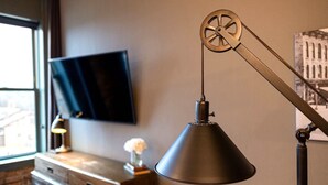 A room with a desk, a television mounted on the wall, and a desk lamp. - 124 Lofts #4 - Downtown Dundee - Walk to Dining (West Dundee)