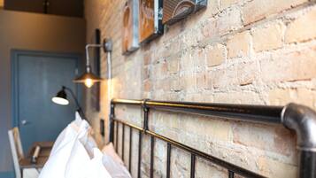 A brick wall with a metal bed frame and a hanging light fixture.