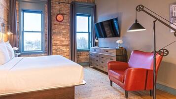 A bedroom with a bed, a red chair, a TV, and a clock on the wall.