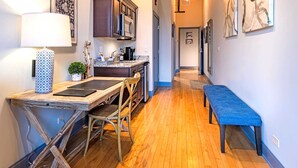 A modern kitchen with wooden flooring, a dining area with a bench, and artwork on the walls. - 124 Lofts #1 - Downtown Dundee - Walk to Dining (West Dundee)