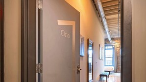 A hallway with a door labeled 'One,' wooden flooring, and hanging pendant lights. - 124 Lofts #1 - Downtown Dundee - Walk to Dining (West Dundee)