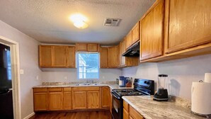 A kitchen with wooden cabinets, a stove, a sink, and a window.
