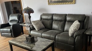 A modern living room with a leather sofa, a coffee table, and a painting on the wall.