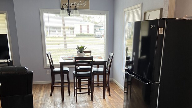 A kitchen with a dining table, chairs, a black refrigerator, and a TV.