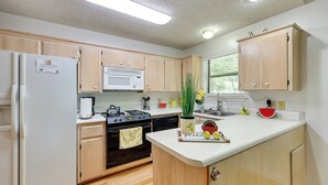 Una cocina moderna con armarios de madera, un refrigerador blanco, un microondas y una estufa.