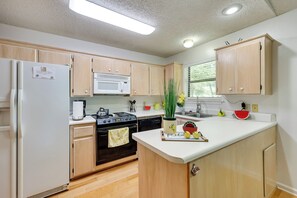 Una cocina moderna con armarios de madera, un refrigerador blanco, un microondas y una estufa.