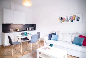 Um espaço de estar moderno com área de jantar, sofá branco e cozinha.