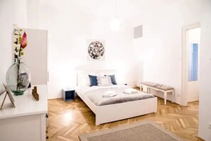 Quarto moderno com cama, mesa de cabeceira e um objeto decorativo na parede.