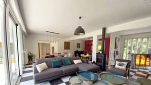 Un salon moderne avec un canapé d’angle, des tables basses en verre et une cheminée.