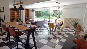 Un espace de vie moderne avec un sol à carreaux, une table à manger en bois avec des chaises, un canapé et une bibliothèque.