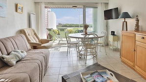 Un salon comprenant un canapé, une table à manger avec des chaises, un téléviseur et un meuble.