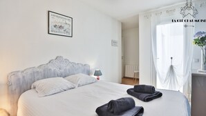 Un lit bien fait, avec des oreillers, une lampe de chevet et des serviettes pliées sur un couvre-lit blanc.
