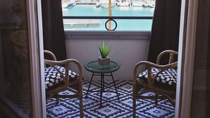 Un balcon avec deux fauteuils en osier, une petite table ornée d’une plante et un sol à motifs.
