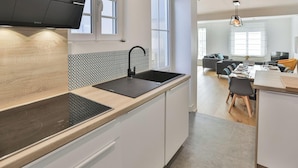 Eine moderne Küche mit einem schwarzen Spülbecken, weißen Schränken und einer gemusterten Spritzschutzwand.