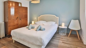 Ein Schlafzimmer mit einem Bett, einem Kleiderschrank, einem Nachttisch mit Lampe und einem Sessel.
