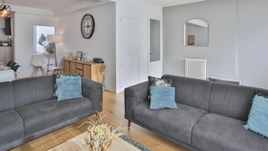 Ein Wohnzimmer mit zwei grauen Sofas, einem Holztisch und einer Heizung.