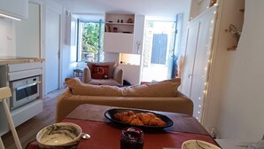 Ett kompakt bostadsutrymme med ett litet kök, en soffa, ett matbord med mat och en tv.