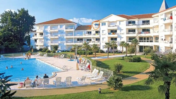 Un hotel con piscina, varios balcones y un césped bien cuidado.