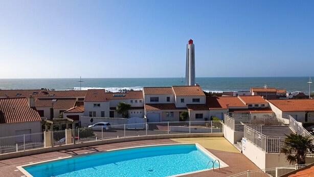Ein Küstenhotel mit Schwimmbad, einem hohen Turm und Meerblick.