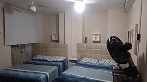 A room with two beds, a ceiling fan, and a wall-mounted projector. - Pelourinho, entire house. (Salvador)
