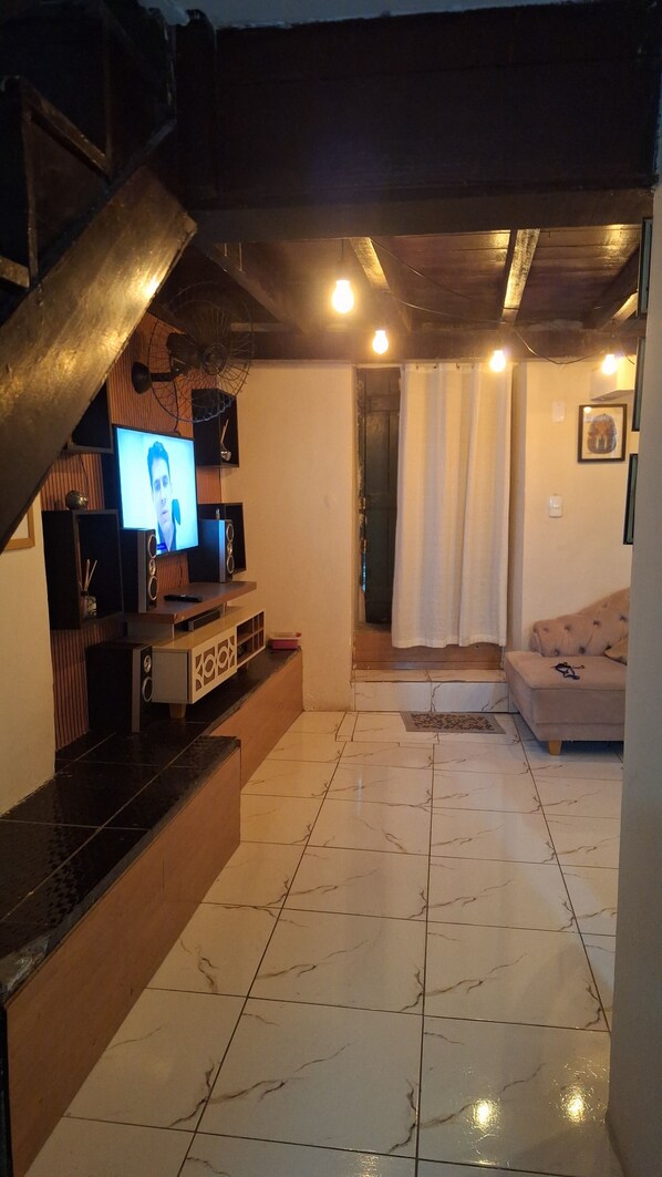 A living room with a TV, speakers, and a staircase.