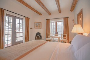Une chambre d’hôtel avec un grand lit, une petite table avec une chaise et une fenêtre avec des rideaux.