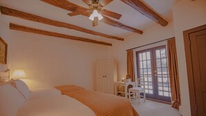 Een hotelkamer met een bed, een bureau en een stoel. Er is een raam met gordijnen en een deur.