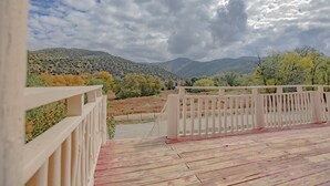 A wooden deck with a white railing overlooking a mountainous landscape.