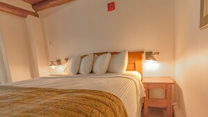 Una camera da letto con un letto, cuscini, un comodino e luci a parete.
