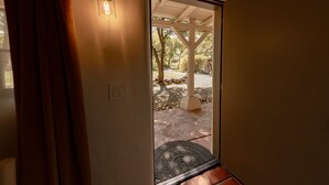 Une porte-fenêtre donnant sur un espace extérieur agrémenté d’une pergola, d’un chemin de pierre et d’un paillasson.