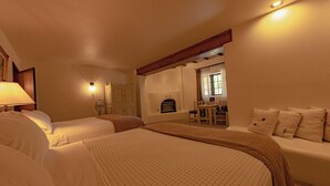 Une chambre d’hôtel avec deux lits, un coin salon avec une table et des chaises, et une cheminée.