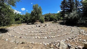 Un arrangement circulaire de pierres, entouré d’arbres, sous un ciel dégagé.