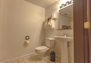 Standard bathroom with a toilet, sink, and mirror, plus a towel rack and storage for essentials.