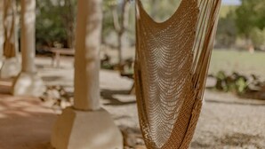 Un hamac est suspendu entre deux colonnes, dans un cadre extérieur.