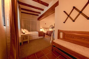Cozy bedroom with a traditional design, featuring a bed with a white headboard and a wooden bench.