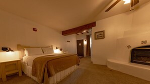 A bedroom with a bed, bedside table, and a fireplace. - Queen room w/ gas fireplace - 16 (Taos County)