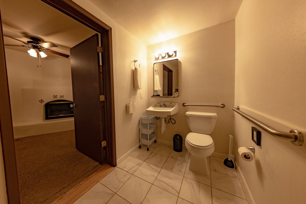 A compact bathroom with a toilet, sink, and mirror.