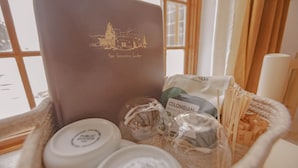 Una cesta con un ordenador portátil que muestra el logo del hotel, un paquete de café colombiano y algunos artículos de aseo.