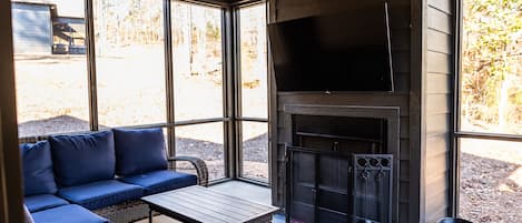 A modern outdoor living area with a sofa, table, and fireplace.