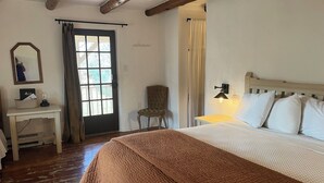 Een slaapkamer met een bed, een stoel, een bureau en een raam met gordijnen.