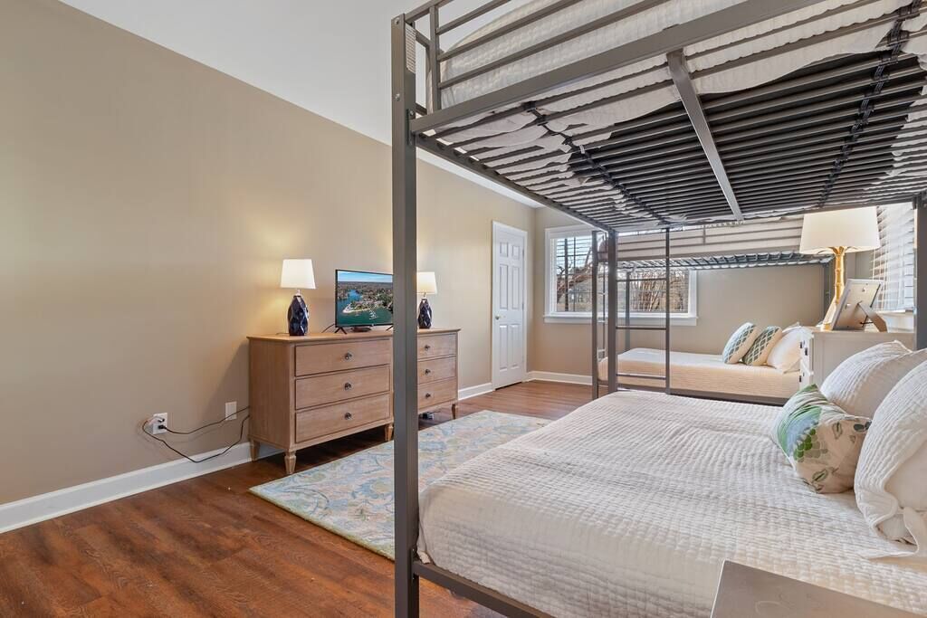 Une chambre avec un lit superposé, une commode, une lampe et une fenêtre.