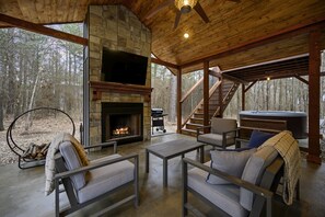 A cozy cabin interior with a stone fireplace, comfortable seating, a hot tub, and a staircase leading to a deck. - The Star Inn - Cabin sleeps 6 with hot tub!  (Broken Bow)