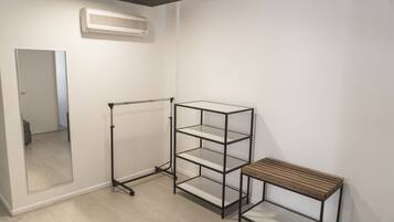 A room with a metal shelving unit, a wooden bench, and a mirror on the wall.