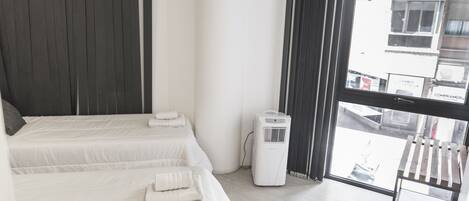 Habitación de hotel con dos camas, una ventana y un radiador independiente.
