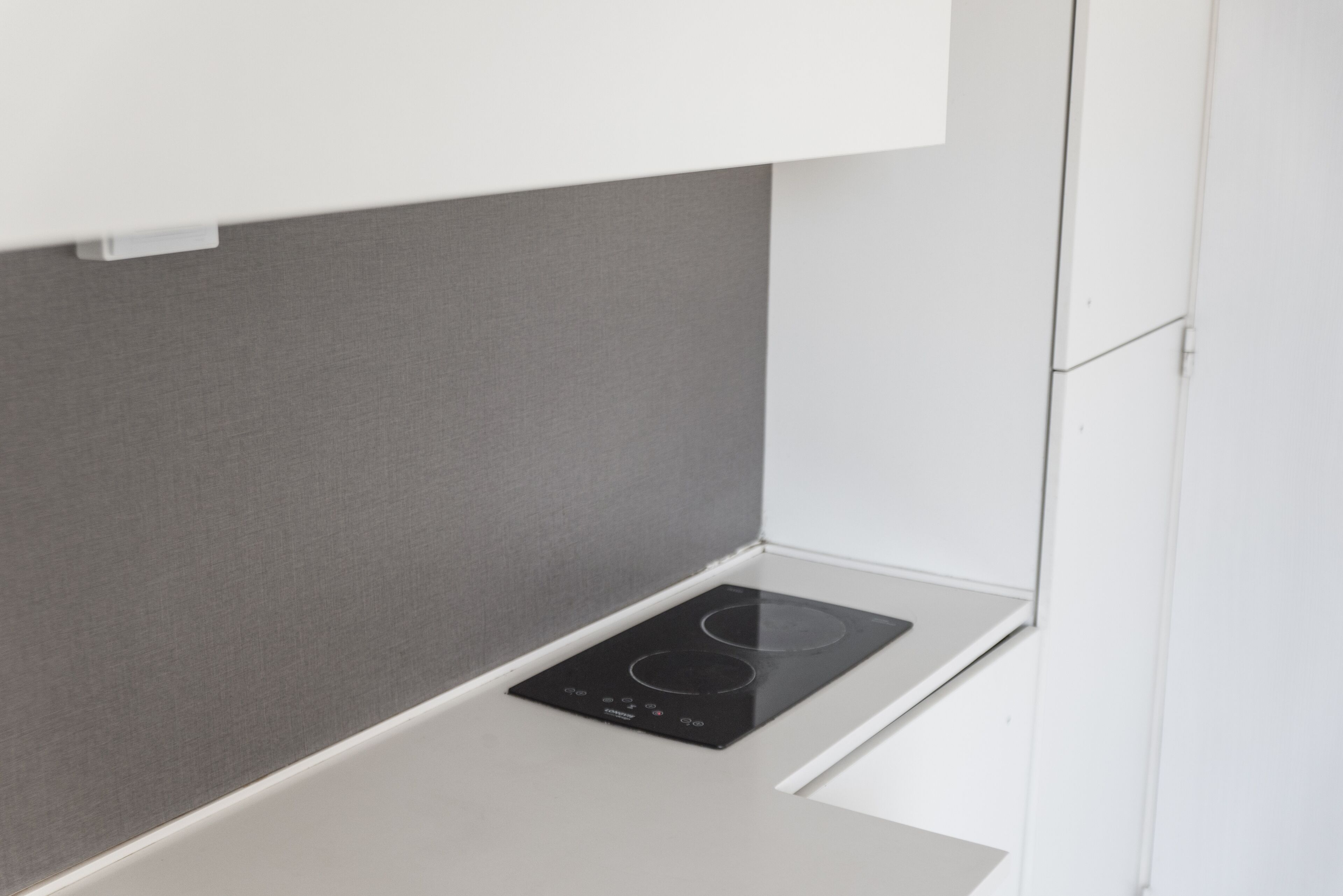 A modern kitchen with a built-in induction cooktop and a white countertop.