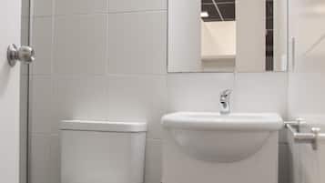 Casa de banho pequena e moderna, com sanita, lavatório e espelho.