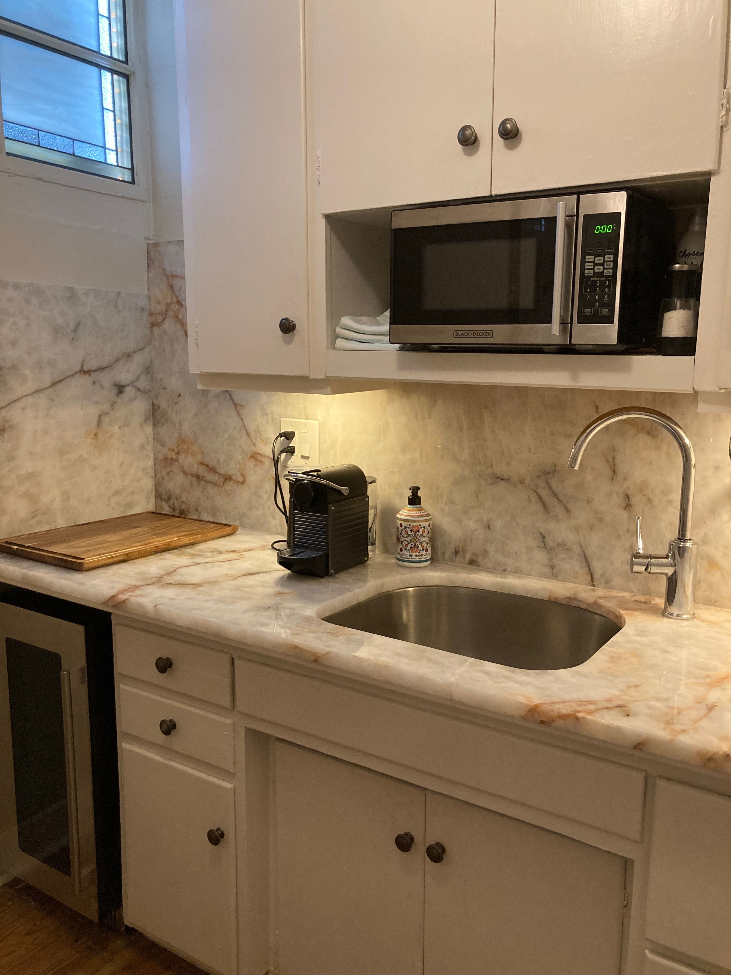 A kitchen with a stainless steel sink, a microwave, and a coffee maker on the countertop.