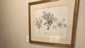 A dining table set with plates, cutlery, and glasses, with a framed botanical illustration on the wall. - Elegant Garden-Level Apt, Beautiful Marble Spa Bath, City Center! 96 Walk Score! (Denver)